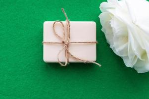 the soap is tied with a rope and a white rose on a green background with a place for the inscription. Concept of hygiene and Spa procedures. photo