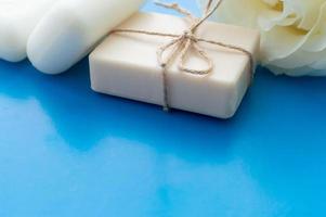 the soap is tied with a rope and a white rose on a blue background with a place for the inscription. Concept of hygiene and Spa procedures. photo