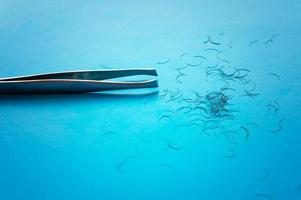 tweezers for plucking eyebrows and hair on a blue background with a place for writing photo