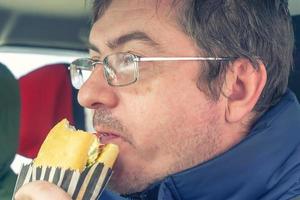 man wearing spectacles eats sandwich photo