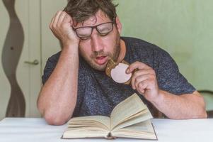 man reading a book at the table, having a snack while reading, a short break photo