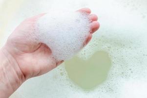 espuma de jabón en la mano de una persona sobre un fondo de espuma de jabón. el concepto de limpieza e higiene.
