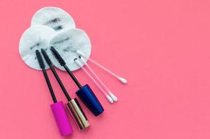 Used dirty cotton pads, mascara brushes and cotton swabs after removing makeup on a pink background with space for writing photo
