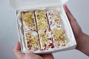 Hands hold a gift box with nougat prepared with their own hands. Work at home. Horizontal photo. photo
