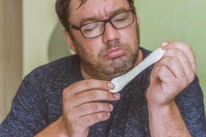 a man with glasses looks at a feminine sanitary pad with surprise photo