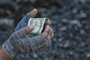 A dollar in the hands of a homeless man in gloves. Poverty, hunger, unemployment. photo