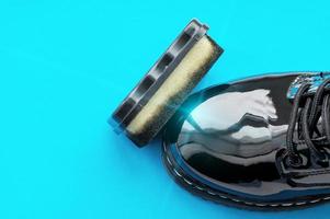 A Shoe sponge next to a polished black patent Shoe on a blue background. photo