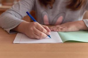 hand of a teenage girl writes with a ballpoint pen in a terad during a lesson at school photo