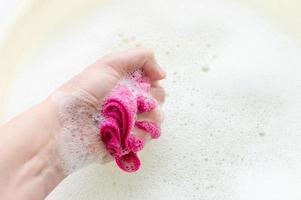 Household rag in hand on the background of soap suds. The concept of household. photo