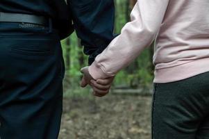 un hombre sostiene la mano de una adolescente en el bosque. el concepto de secuestro y trata de niños. foto