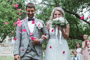 bride and groom at the wedding ceremony. congratulations of the guests. showering with rose petals. selective focus. film grain. photo