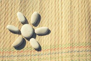 A figure of the sun made of sea pebbles on a straw blanket. Cute children's games on the beach. The concept of tourism and beach holidays. photo