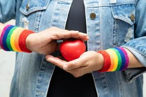 dama asiática con pulseras de arco iris y corazón rojo, símbolo del mes del orgullo lgbt celebran anualmente en junio las redes sociales de gays, lesbianas, bisexuales, transgénero, derechos humanos.
