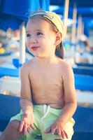 A happy smiling boy in shorts and a cap by the sun loungers on a Sunny day. Tourism, travel, family vacations. photo