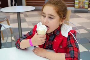 teenage girl eating ice cream in a cone at a food court mall. Unhealthy food. photo