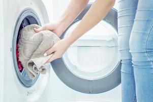 women's hands put Laundry in the washing machine. Housekeeper. Close up. Selective focus. Film grain photo