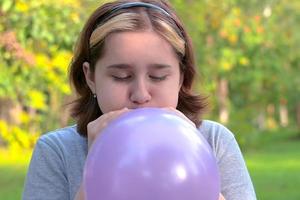 teenage girl inflated a big blue balloon in nature in the park photo