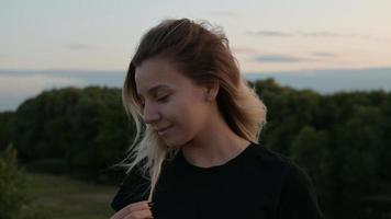 portrait of a beautiful smiling blonde girl with loose hair standing in the wind against the background of autumn nature at sunset concept of emotions photo