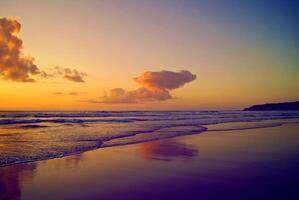 sunset orange in sea and sky blue beautiful sea and sunset with large yellow sun under the sea surface hills in the background. photo