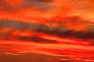 nubes naranjas y grises hermoso ambiente al atardecer con un gran sol amarillo y naranja en las colinas de la superficie del cielo. foto