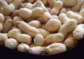 Baked and salted peanuts in a shell. Close up photo in a bowl.
