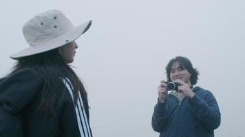 coppia che scatta foto in cima alla montagna con una fitta nebbia sullo sfondo video