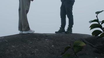 coppia che scatta foto in cima alla montagna con una fitta nebbia sullo sfondo video