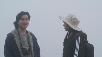 Pareja tomando fotos en la cima de la montaña con una espesa niebla de fondo video