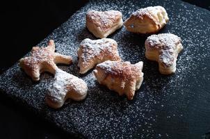 tasty background of cinnamon cakes from puff pastry  on a black slate background photo