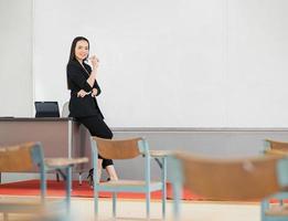 A young Asian teacher stands in front of a classroom at the university. photo