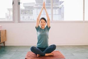 Young Asian woman doing yoga at home photo