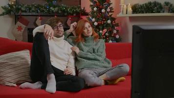 Beautiful couple watching TV during the winter holidays. video