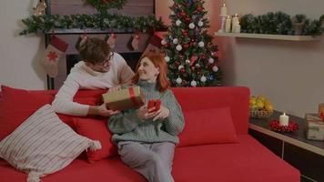 Happy man is making surprise, christmas gift to his beloved woman. video