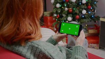 femme tenant un smartphone à clé chroma à écran vert, période de Noël. video