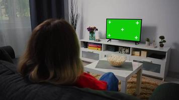 mujer viendo televisión de pantalla verde chroma key, relajante sentado en un sofá en casa. video