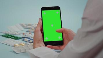 Doctor hand swipes on the smart phone, green screen video