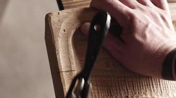 Schreiner verarbeitet Holzplatten mit Spokeshave