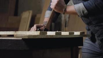 Man pulls nails out of planks with  claw hammer