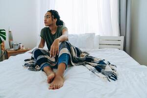 Sad African American woman with a blanket looks to the side at her home photo