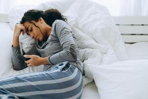 Young black woman using mobile phone lying in bed photo