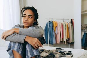 Young black woman using mobile phone while sitting on bed photo