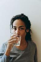 Joven mujer negra bebiendo agua durante pasar tiempo en casa