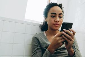 mujer negra, utilizar, teléfono móvil, mientras, posición, en, baño