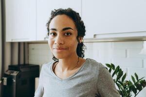 Joven negra sonriendo y mirando a la cámara en la cocina foto