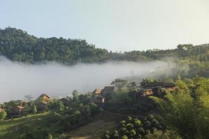 Village thailand with foggy landscape mountains misty forest with tree and house in the moring winter nature - View of foggy house on hill countryside photo