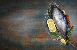 Fresh fish with herbs spices rosemary tomato and lemon - Raw fish seafood on black plate background , Longtail tuna , Eastern little tuna fish photo