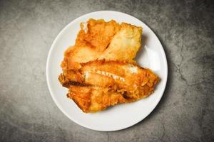 Filete de pescado frito en rodajas para cocinar bistec o ensalada, espacio de copia de vista superior - filete de tilapia crujiente de pescado servido en un plato blanco foto