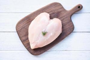 raw chicken meat with rosemary on wooden cutting board fresh raw chicken breast heart shaped fillet on wood health food concept photo