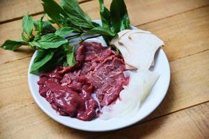 Conjunto de rebanada de carne de res, hígado y champiñones, verduras en un plato blanco para alimentos japoneses cocidos o sukiyaki shabu shabu foto