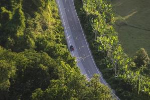 Road view from above with tree in the countryside asian - Aerial view over mountain road going through forest landscape and agricultural area photo